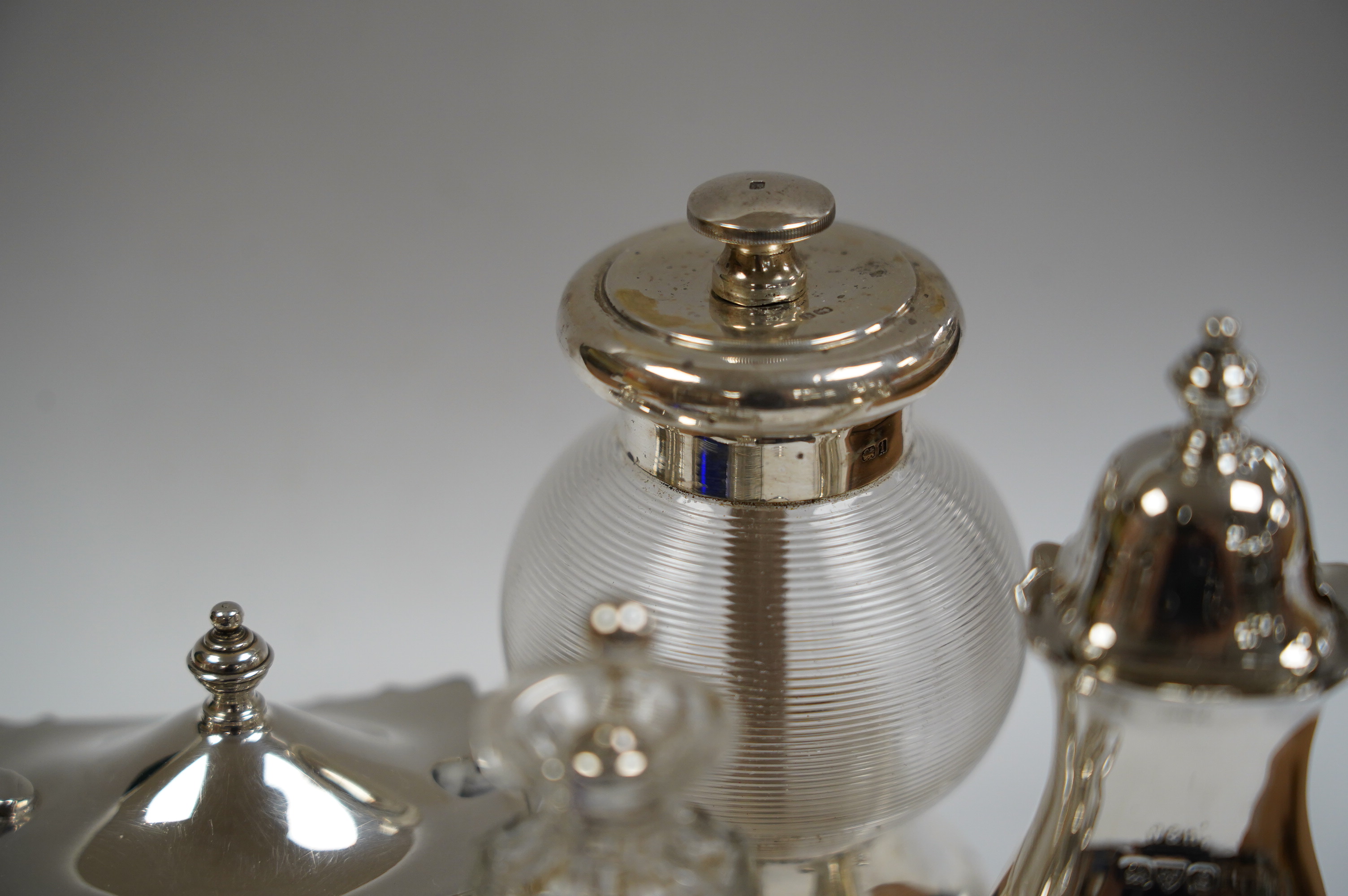 Six assorted silver condiments including a mounted ribbed glass pepper grinder and an Edwardian mounted glass cayenne pepper condiment, Condition - fair to good